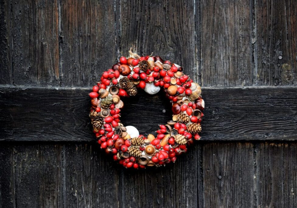 A wreath of red berries and nuts hanging on the side of a door.